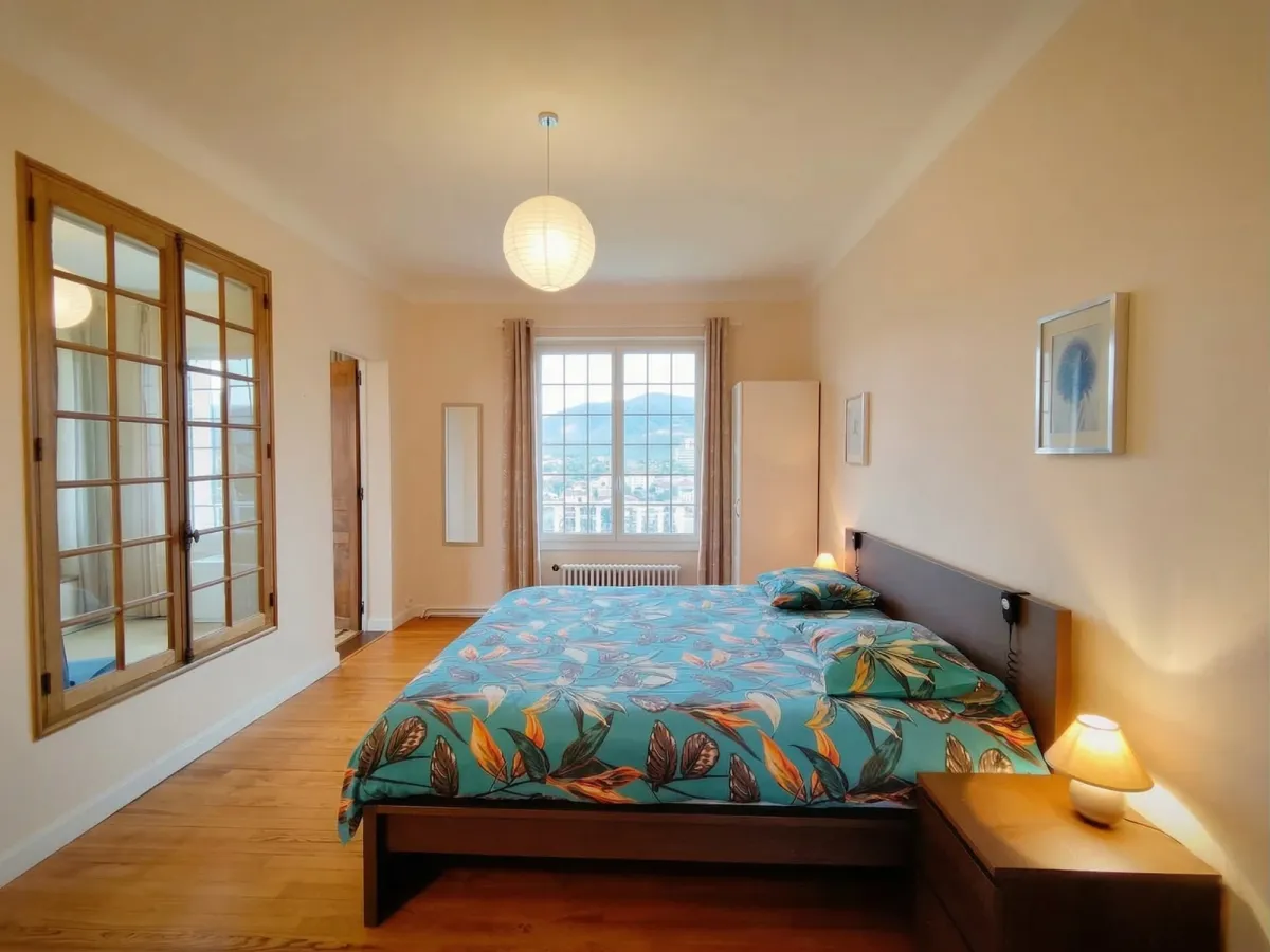 Chambre avec draps bleus à motifs et grande fenêtre vers les montagnes