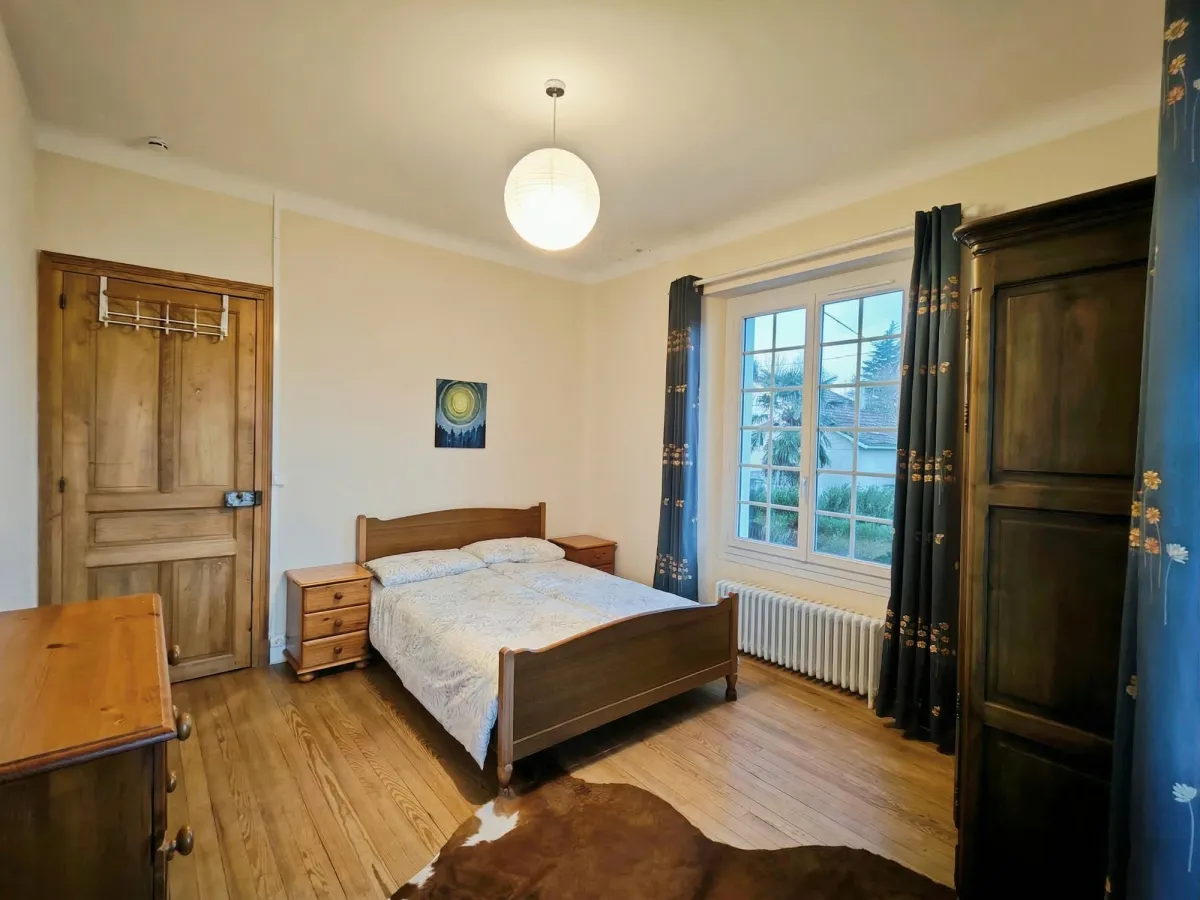 Chambre avec lit en bois, armoire ancienne et grande fenêtre
