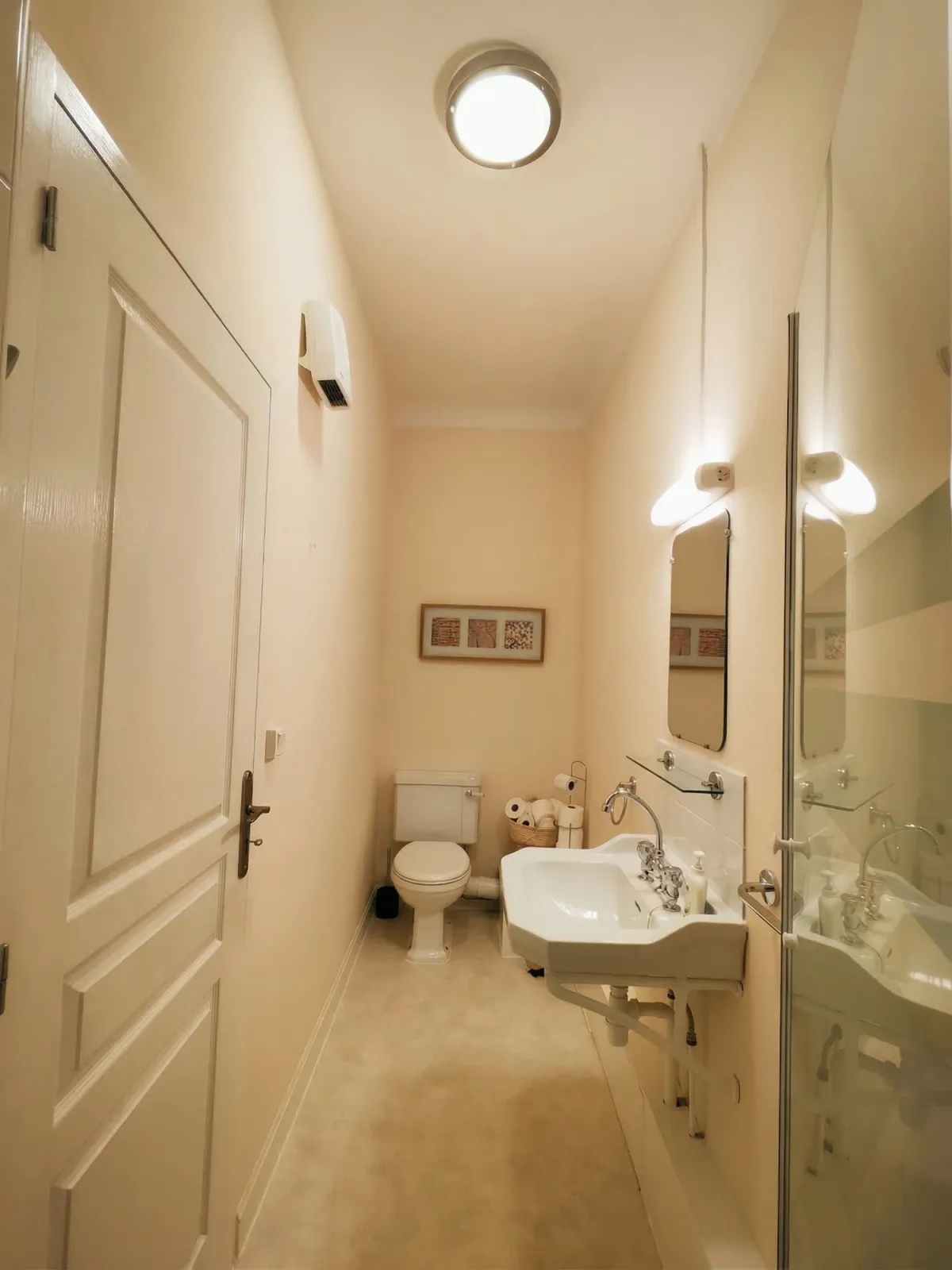 Salle d’eau étroite avec lavabo, miroir et toilettes