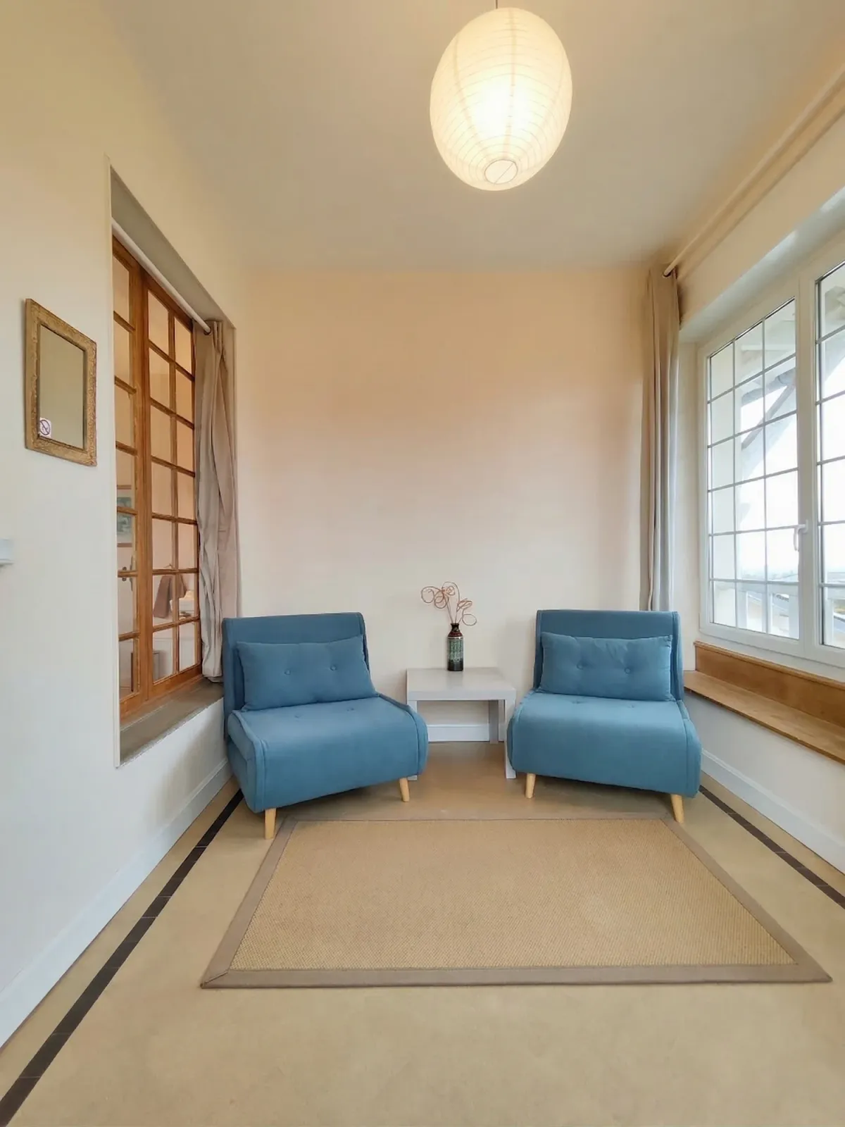 Coin salon avec deux fauteuils bleus près du parquet
